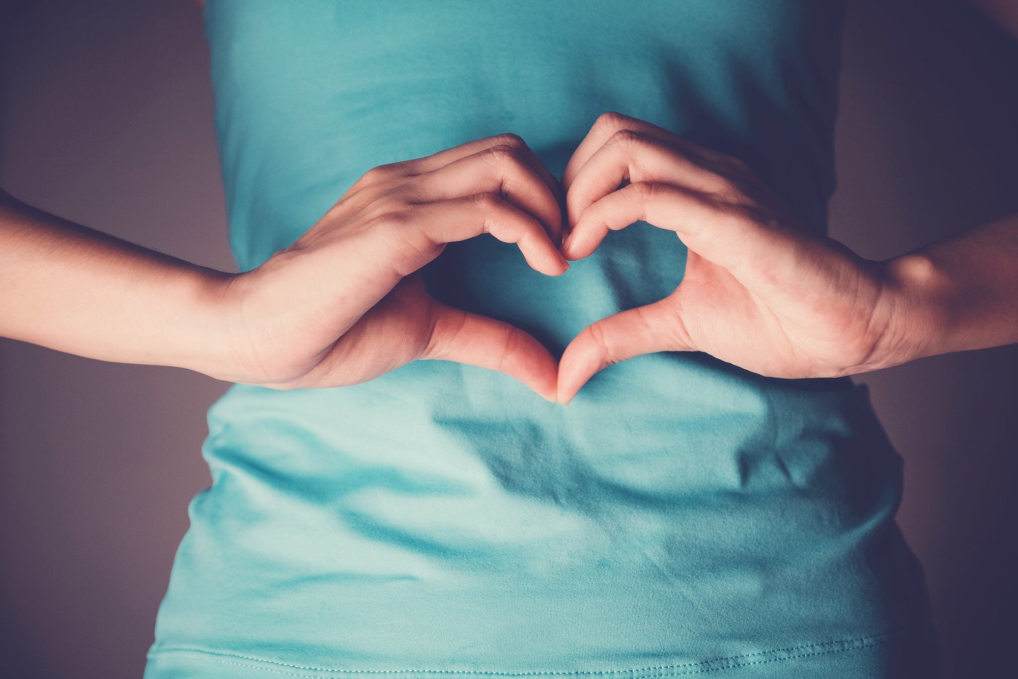 Woman making a heart with her hands next to her stomach