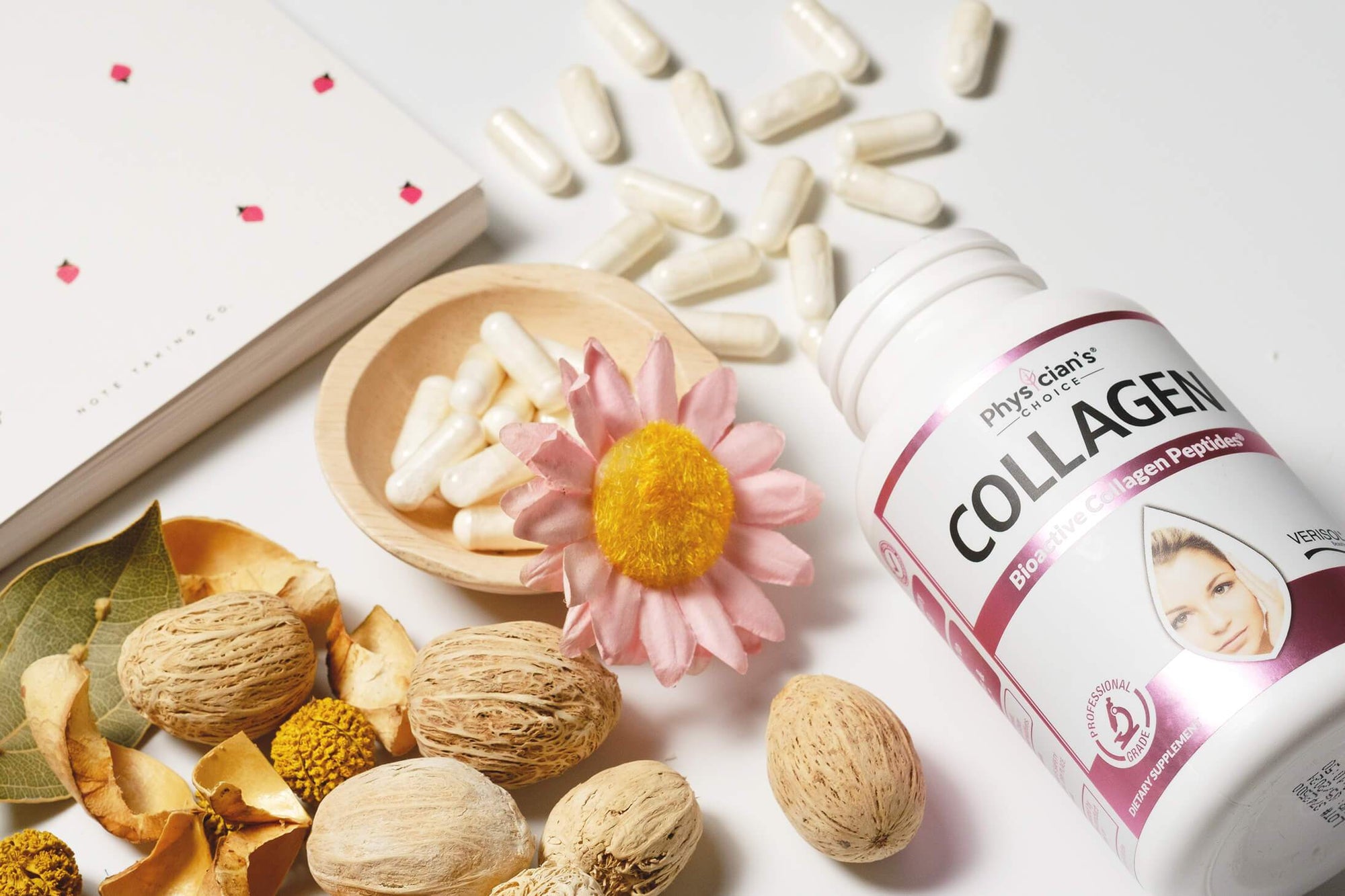 Physician's Choice collagen supplements next to flowers, nuts, and a notebook