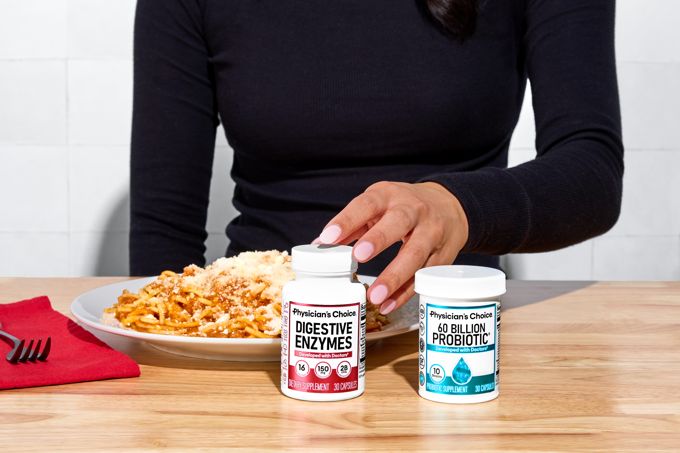 Both bottles on a kitchen table beside a plate of food at mealtime