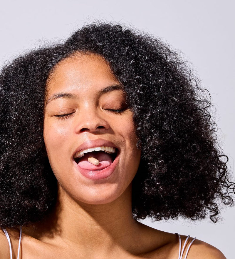Woman laughing with a capsule on her tongue