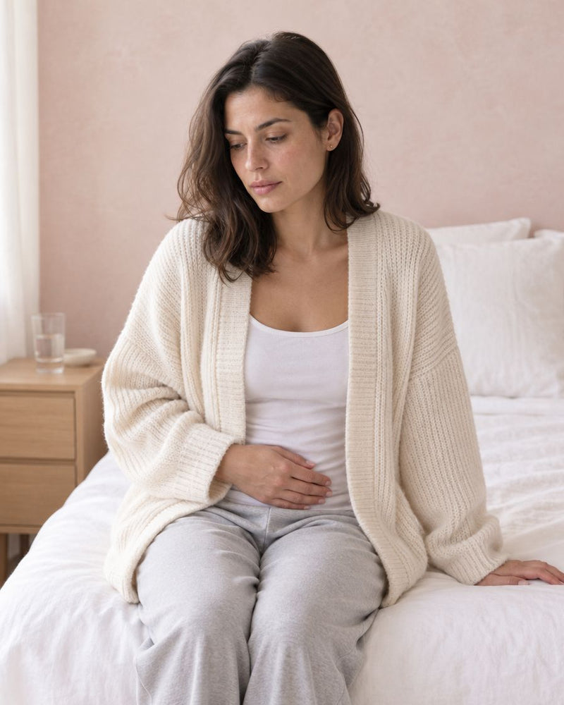 Woman sitting on her bed in the morning, thoughtful